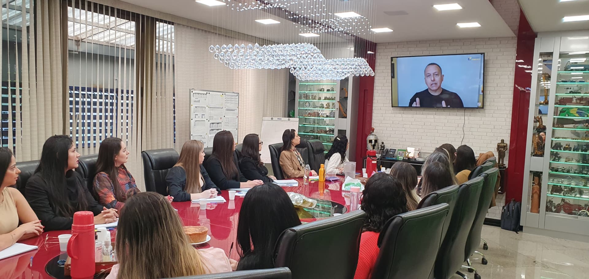 Rogério Chelucci conduzindo mentoria por videochamada para equipe reunida em sala de reunião